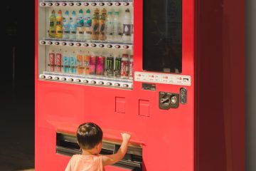 a little boy playing with a vending machine